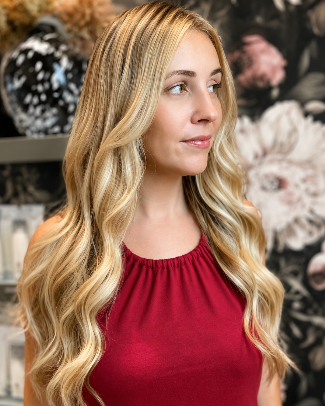 Client showing long blonde balayage hair extensions styled in loose waves, front view