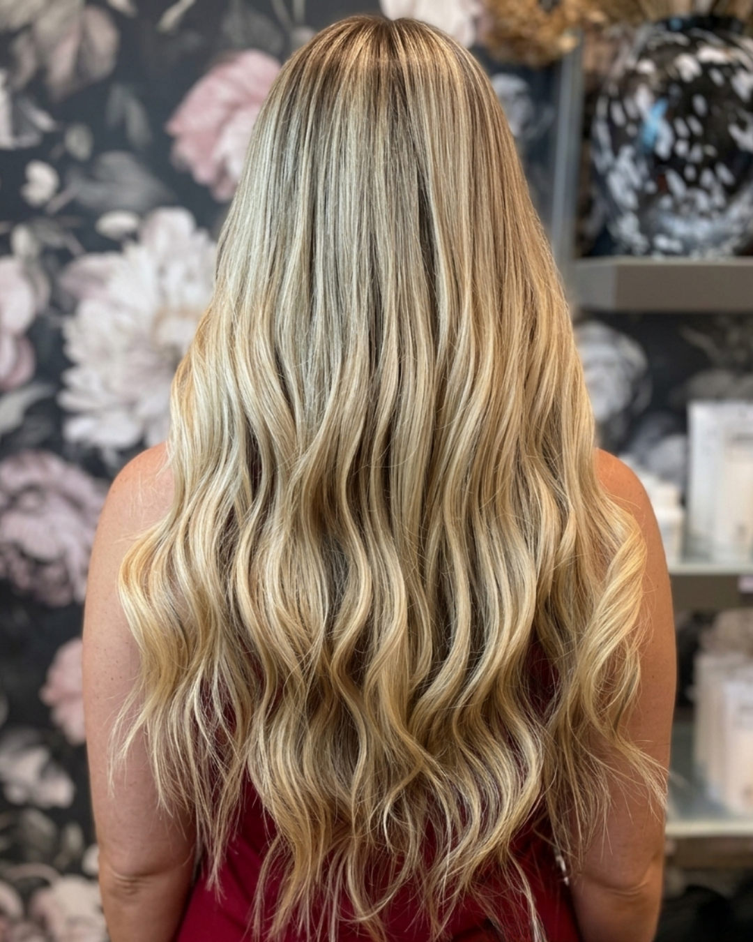 Client showing long blonde balayage hair extensions styled in loose curls, back view