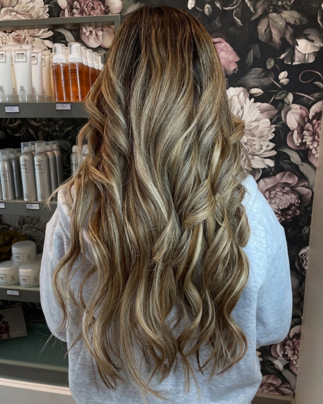 Client showing long brunette hair extensions with soft highlights, back view